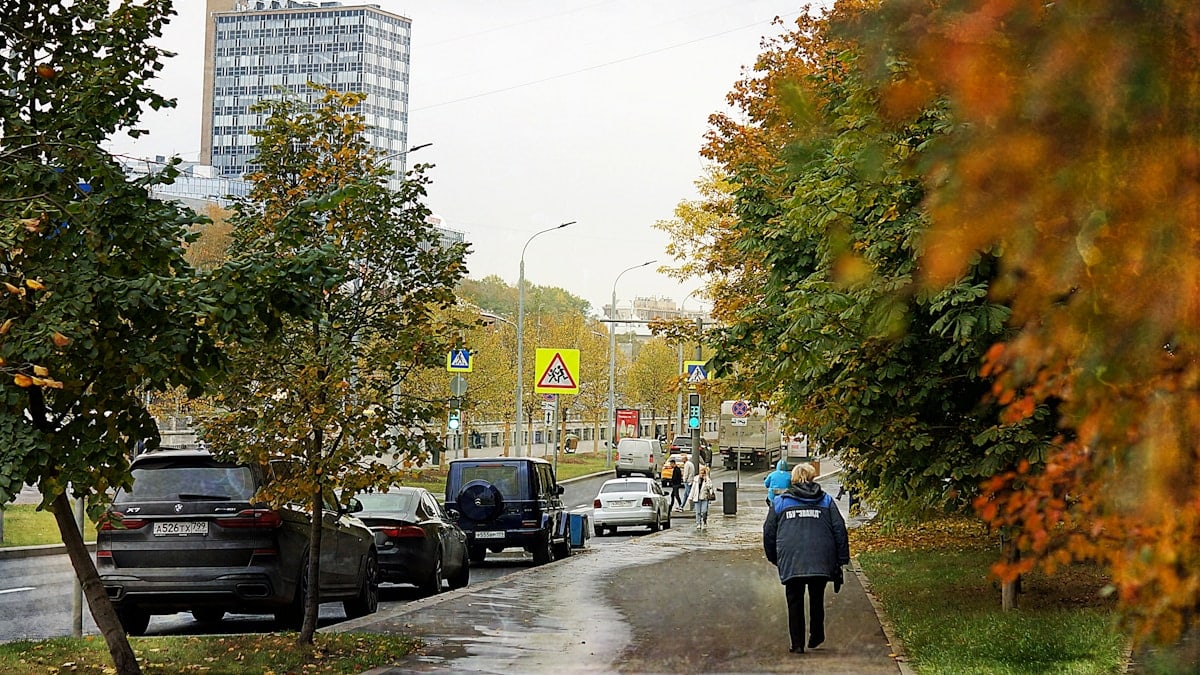 Autumn street with cars and a pedestrian